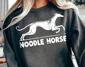 Pode incluir: Uma camisa de moletom cinza escura com um gráfico branco de um galgo estilizado correndo e o texto "NOODLE HORSE".
