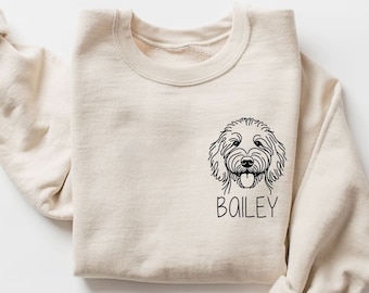 May include: A beige sweatshirt with a black line drawing of a dog's head and the name "BAILEY" printed below.