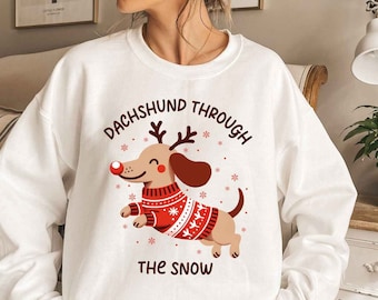 May include: White sweatshirt with a red and white dachshund wearing a red and white sweater and the text "Dachshund Through The Snow".