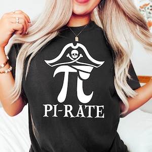 以下が含まれることがあります： 白いパイレーツハットとドクロとクロスボーンのグラフィックが描かれた黒いTシャツ。数学記号のパイの上にドクロとクロスボーンが描かれています。グラフィックの下に「パイレーツ」というテキストがあります。