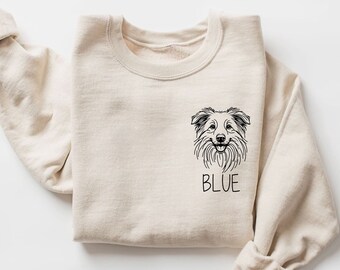 Puede incluir: Una sudadera beige con una ilustración en blanco y negro de la cabeza de un perro y la palabra "BLUE" impresa en la parte delantera.