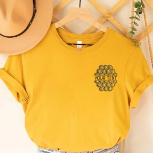 May include: A yellow t-shirt with a black honeycomb design and the text "YOUR TEXT" on the front.