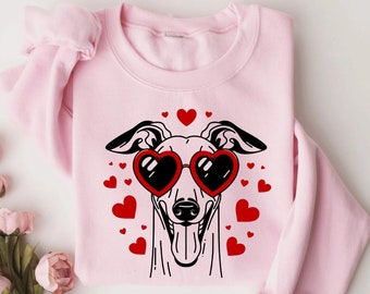 May include: Pink sweatshirt with a black and white illustration of a dog wearing heart-shaped sunglasses. The dog is surrounded by red hearts.