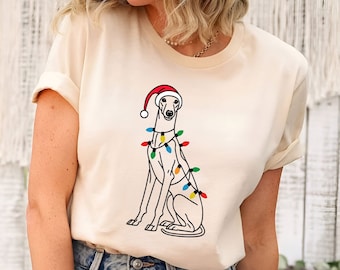 May include: A white t-shirt with a black and white illustration of a dog wearing a Santa hat and Christmas lights.