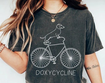 Doxycyclin Wortspiel-T-Shirt | Dackel Fahrrad Tee | Lustiges Apotheker Geschenk | Lustiges Tierarzt-Hemd | Apotheken-Tech-Shirt | T-Shirt