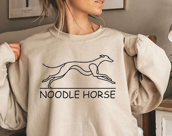 Pode incluir: Uma camisa de moletom bege com um desenho de linha preta de um galgo correndo e o texto "NOODLE HORSE" abaixo.