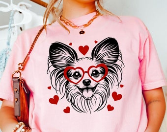 Puede incluir: Una camiseta rosa con una ilustración en blanco y negro de un perro con gafas en forma de corazón. El perro está rodeado de corazones rojos.
