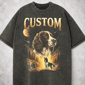 May include: Dark gray t-shirt with a dog graphic and the word "CUSTOM" in gold lettering. The graphic features a dog's portrait, a smaller dog, a waterfall, and a forest scene. The shirt has a vintage, worn look.