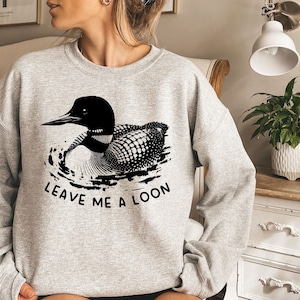 May include: A gray sweatshirt with a black and white loon graphic and the text "Leave me a loon".