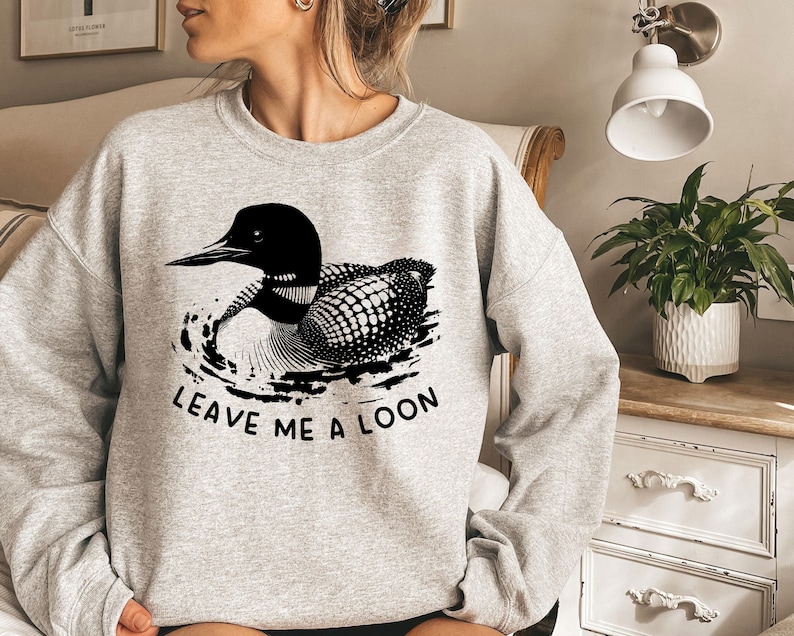 May include: A gray sweatshirt with a black and white loon graphic and the text "Leave me a loon".