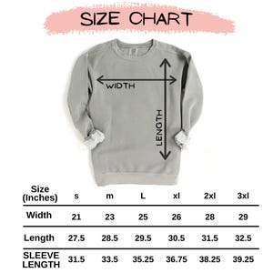 May include: A light gray sweatshirt with a size chart. The chart displays measurements in inches for width, length, and sleeve length, ranging from size small to 3XL. The text "SIZE CHART" is at the top.