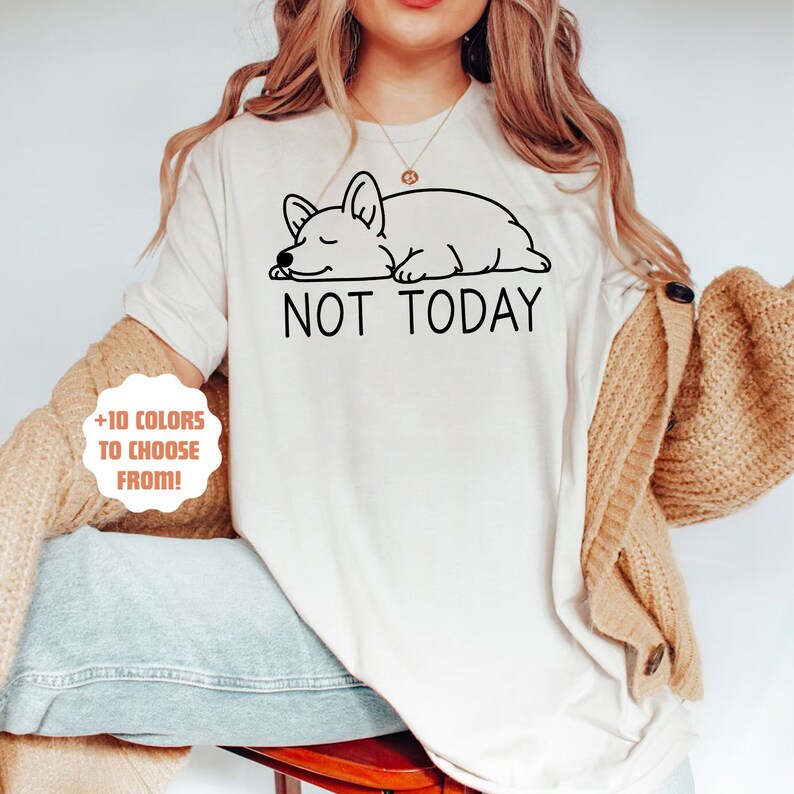 May include: A white t-shirt with a black line drawing of a sleeping corgi and the text "NOT TODAY".