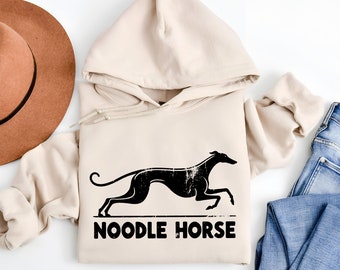 Pode incluir: Um moletom bege com uma silhueta preta de um galgo correndo e o texto "NOODLE HORSE" impresso na frente.