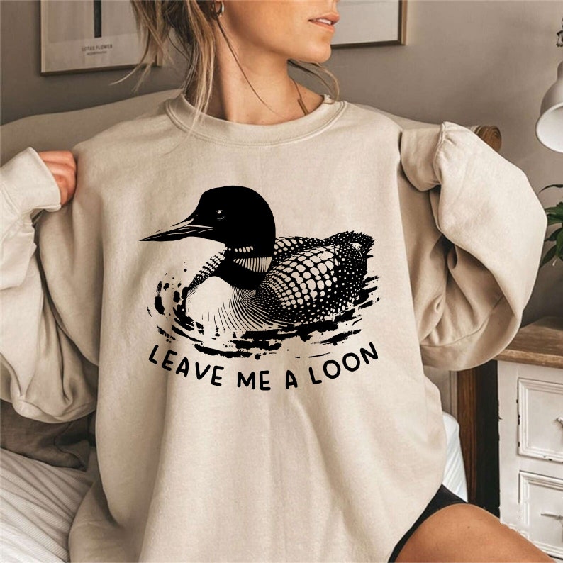 May include: A beige sweatshirt with a black loon graphic and the text "Leave me a loon".