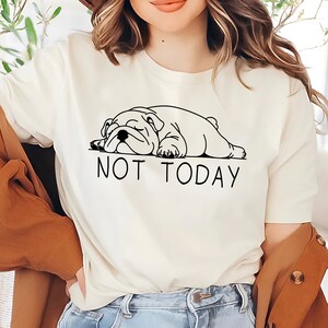 May include: White t-shirt with a black line drawing of a bulldog sleeping and the text "NOT TODAY" underneath.