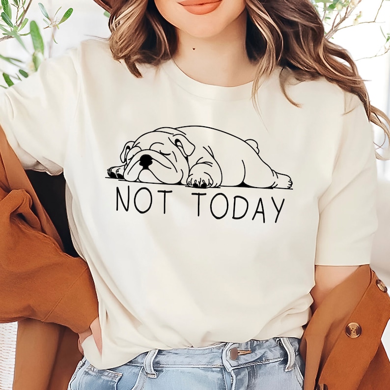 May include: White t-shirt with a black line drawing of a bulldog sleeping and the text "NOT TODAY" underneath.