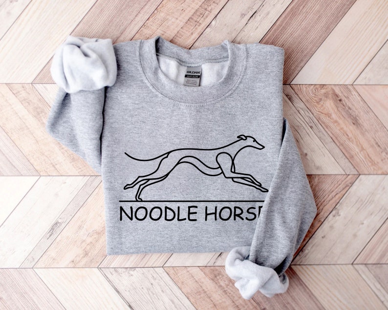 May include: Gray sweatshirt with a black line drawing of a greyhound dog running and the text "NOODLE HORSE" underneath.