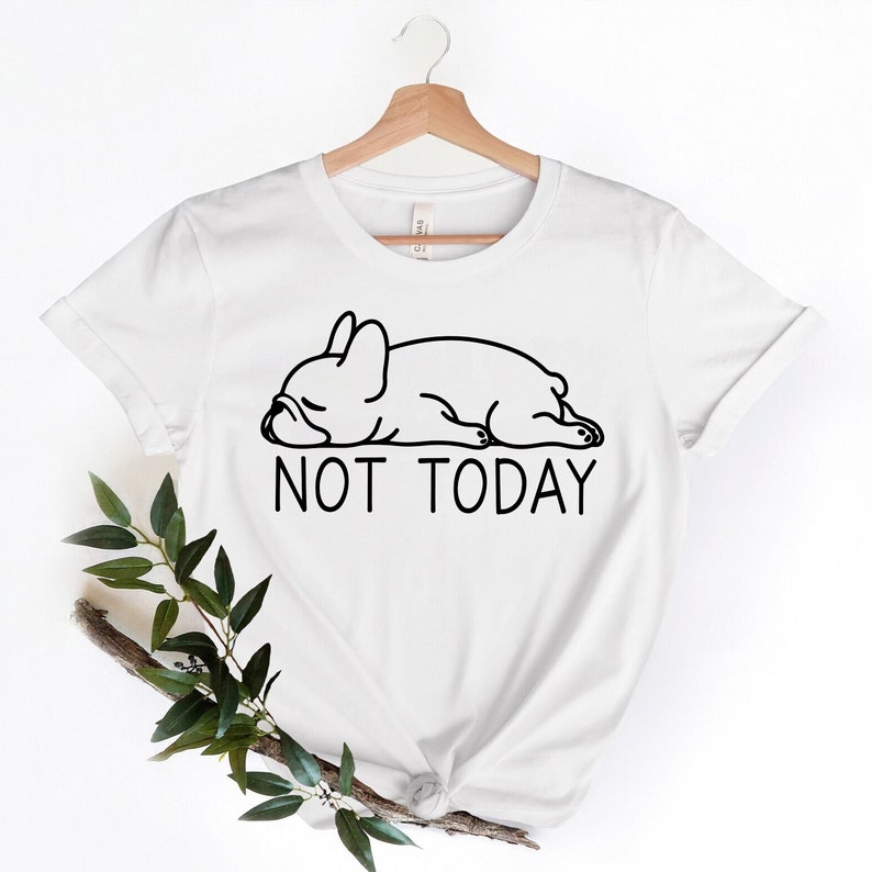 May include: White t-shirt featuring a black line drawing of a sleeping French bulldog and the text "NOT TODAY".