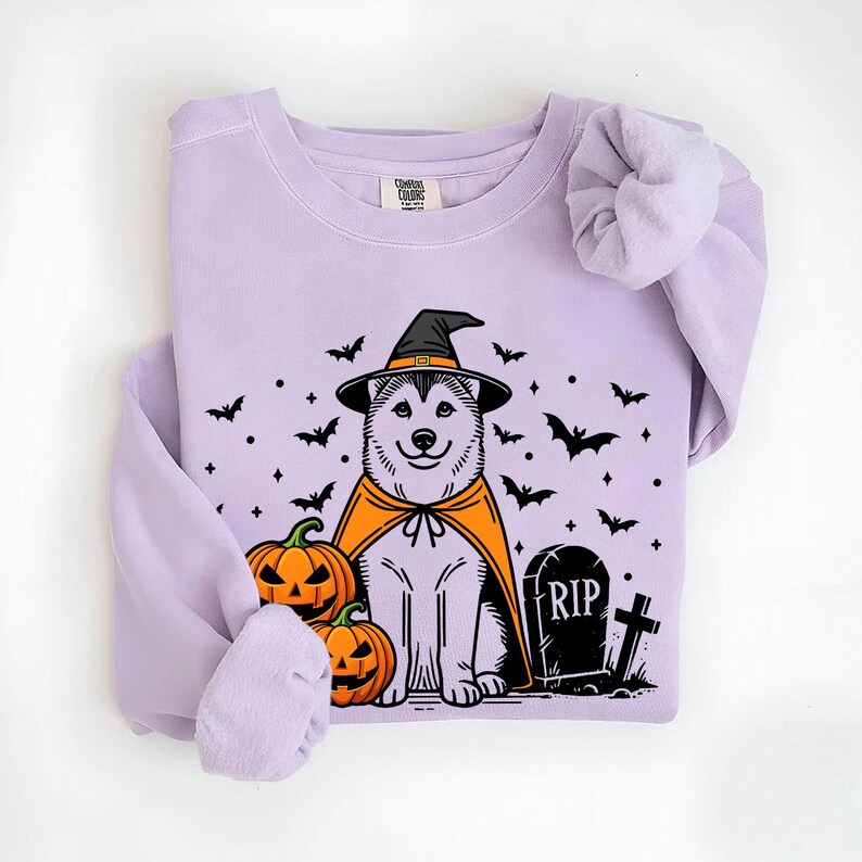 May include: Purple sweatshirt with a graphic of a husky dog wearing a witch hat and cape. The dog is surrounded by bats and pumpkins. The text "RIP" is on a tombstone.