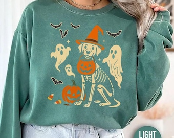 Może przedstawiać: Jasnozielona bluza z motywem Halloween. Projekt przedstawia szkielet psa w kapeluszu czarownicy trzymającego dynię. Duchy, nietoperze i cukierki dopełniają świąteczny wygląd.