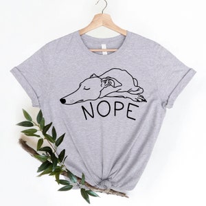 May include: A gray t-shirt with a black line drawing of a dog sleeping with the word "NOPE" printed below it.