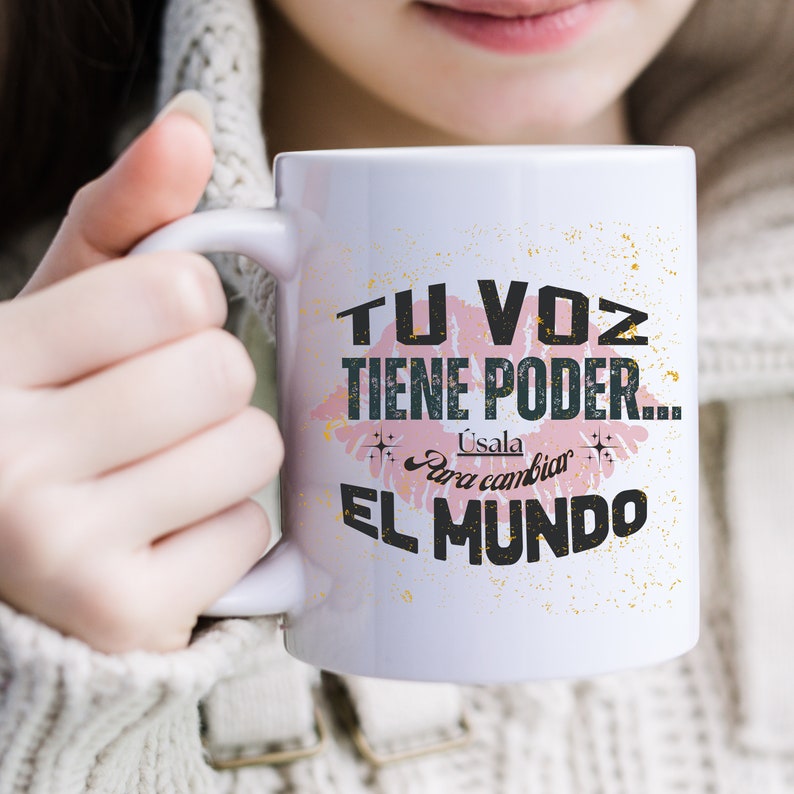 Pu&ograve; includere: Una tazza in ceramica bianca con un design a labbra rosa e il testo "Tu voz tiene poder... Usala para cambiar el mundo" in lettere nere.