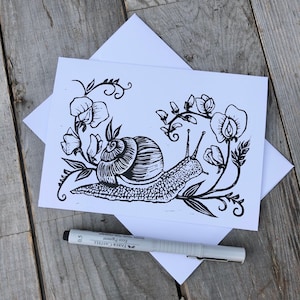 Könnte beinhalten: Schwarz-weiß-Illustration eines Schnecken, der auf einer Rebe mit zarten Blüten kriecht. Die Schnecke ist detailliert mit einem Gehäuse und einem Körper. Die Blüten sind stilisiert und haben ein schlichtes Design.