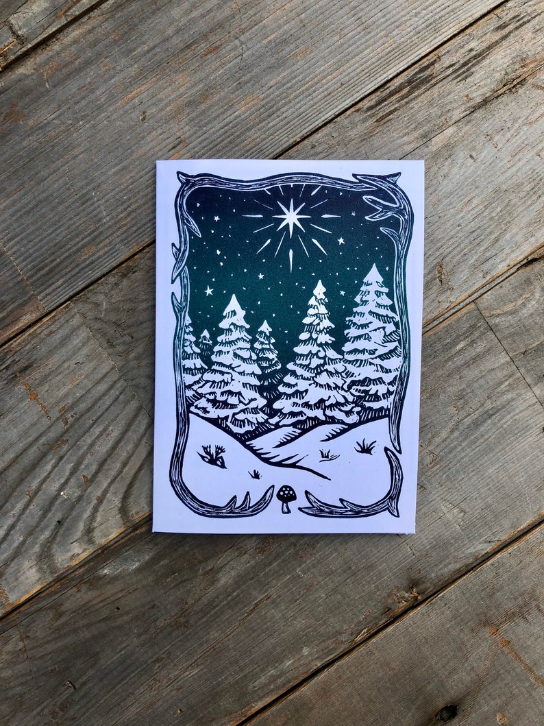 Puede incluir: Una ilustraci&oacute;n en blanco y negro de una escena de bosque nevado con una estrella en el cielo. Los &aacute;rboles son altos y delgados, y la nieve cae suavemente. Hay un peque&ntilde;o hongo en primer plano.