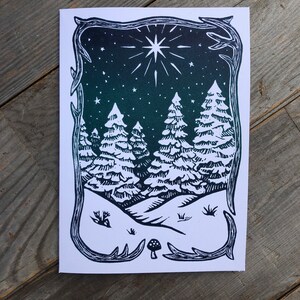 Puede incluir: Una impresi&oacute;n en lin&oacute;leo en blanco y negro de una escena de bosque de invierno con una gran estrella en el cielo nocturno. La impresi&oacute;n est&aacute; enmarcada con un borde decorativo.
