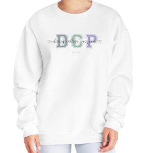 May include: White sweatshirt with the text "DCP Disney College Program" in a collegiate style font. The letters "DCP" are in blue, green, and purple. The text "EST 1981" is below the main text.