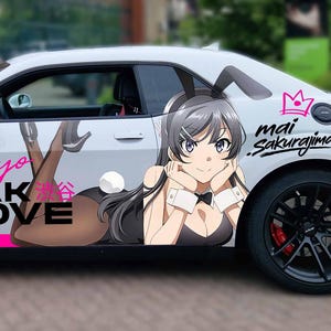 May include: A white sports car featuring a custom vinyl wrap with anime-style graphics. The design includes the text Tokyo BREAK LOVE, JAPAN, and Mai Sakurajima, alongside a character illustration wearing bunny ears and a black outfit on the side panel.