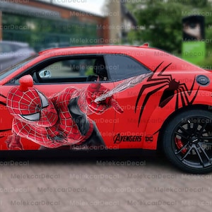 May include: A red car with black wheels and a Spider-Man theme. The car features a large Spider-Man graphic on the side, along with black spider web designs and the text "SPIDER-MAN" on the back.