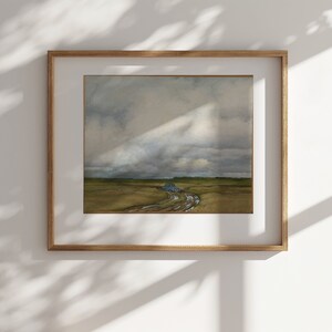 Puede incluir: Una pintura al agua enmarcada que representa un coche azul conduciendo por un camino de tierra en un campo. El cielo está nublado y el sol brilla a través de las nubes.