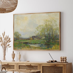Peut inclure: Une peinture de paysage encadrée représentant une scène rurale avec une ferme, des arbres et un ruisseau. La peinture est réalisée dans un style impressionniste doux avec des couleurs douces de vert, bleu et marron.