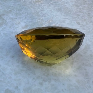 May include: A large, faceted, golden-brown gemstone with a smooth, polished surface.