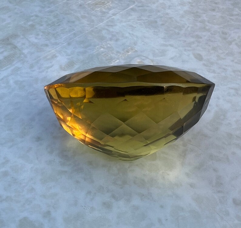 May include: A large, faceted, golden-brown gemstone with a smooth, polished surface.