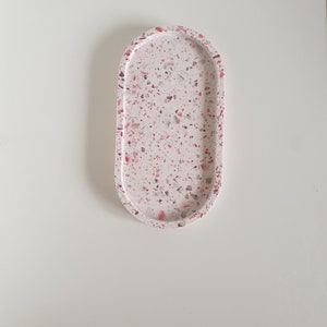 Può includere: Un vassoio ovale bianco con un motivo in terrazzo rosa e grigio. Il vassoio è perfetto per contenere gioielli, chiavi o altri piccoli oggetti.
