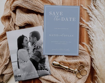 May include: A blue save the date card with white text that reads "Save the Date" and "For the Wedding of Katie and Dylan". The card also includes the date "Saturday January 21, 2024" and the location "Calgary, Alberta".