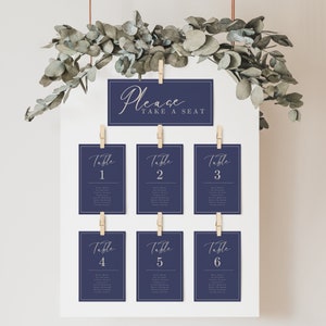 May include: A navy blue seating chart with white text. The top sign says "Please Take A Seat". The other signs are numbered 1 through 6 and list names for each table.