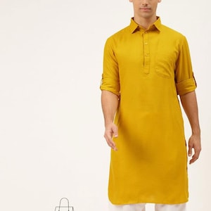 May include: A mustard yellow long-sleeved kurta with a button-up collar and a single pocket on the chest. The kurta is worn with white trousers.