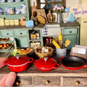 May include: A miniature kitchen set featuring red cookware, a wooden utensil holder, and a basket of miniature eggs. The set is displayed on a wooden countertop with a drawer.