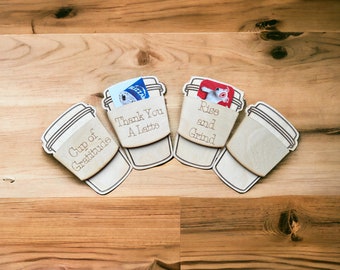 May include: Four wooden coffee cup holders with gift cards inside. The holders are engraved with the text "Cup of Gratitude", "Thank You A Latte", "Rise and Grind", and a blank holder.