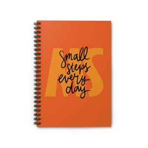 May include: Orange spiral notebook with the text "small steps every day" in black lettering on a yellow background.