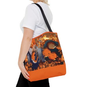 May include: Orange tote bag with black straps featuring a graphic of the word "N.O.I.S.E." in flames.