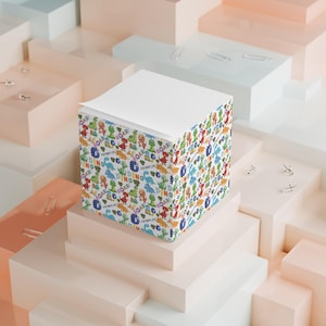 May include: A white notepad with a colourful dinosaur pattern. The notepad is on a stack of white and beige boxes.