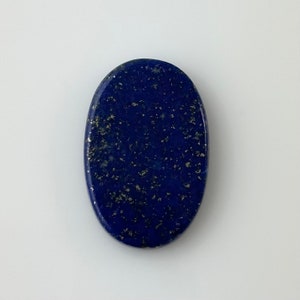 May include: Oval shaped lapis lazuli cabochon with a deep blue color and gold flecks.