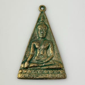May include: A triangular brass pendant with a green patina depicting a seated Buddha figure. The pendant has a loop at the top for hanging.