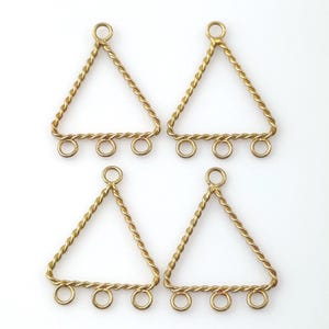 May include: Four gold-colored triangle-shaped jewelry components. Each triangle has a twisted wire frame with three small loops at the base and a single loop at the top. The components are designed for jewelry making.