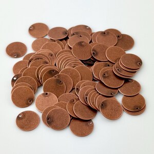 May include: A pile of round copper metal discs with two small holes in each disc.