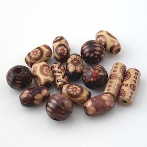 May include: A collection of wooden beads in various shapes and sizes. The beads feature a mix of natural wood tones, with some displaying intricate patterns in shades of brown and red. The assortment includes round, oval, and cylindrical beads, suitable for jewelry making.